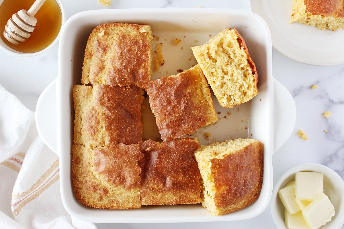 Pieces of cornbread scattered in a white baking dish.