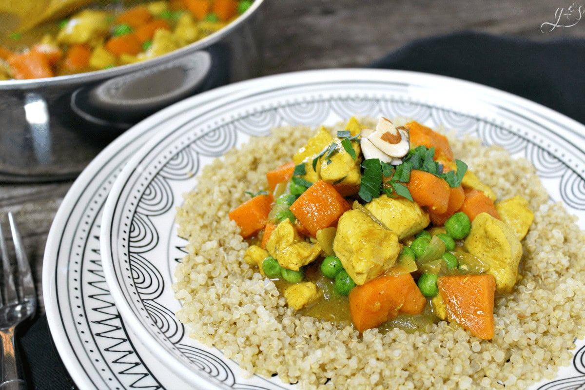 Chicken Sweet Potato Curry on top of quinoa on a white and black decorative plate.