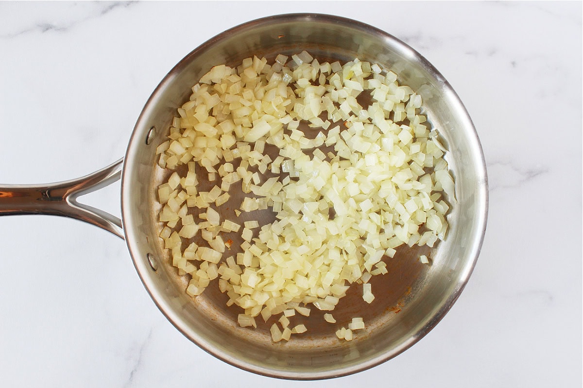 Sauteed onion in a stainless steel sauté pan.