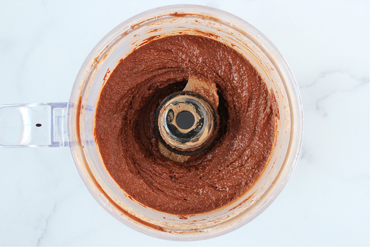 Smooth brownie batter dessert hummus in a food processor bowl.