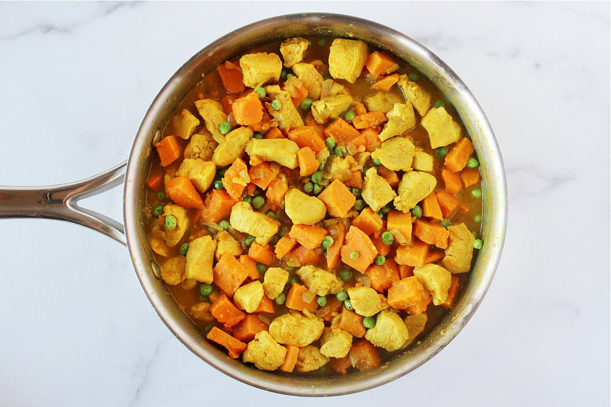 Bite-size pieces of chicken breast and sweet potato with green peas in a curry sauce.