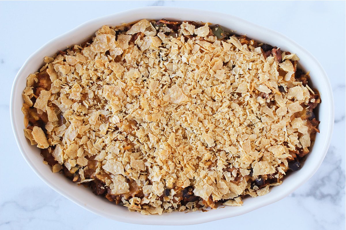 Baked ground beef enchilada casserole in a oval baking dish.