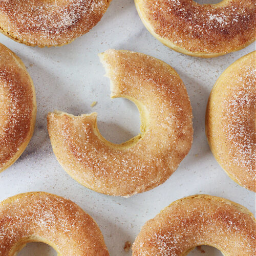 A bite taken out of the middle cinnamon sugar donut surrounded by golden brown donuts.