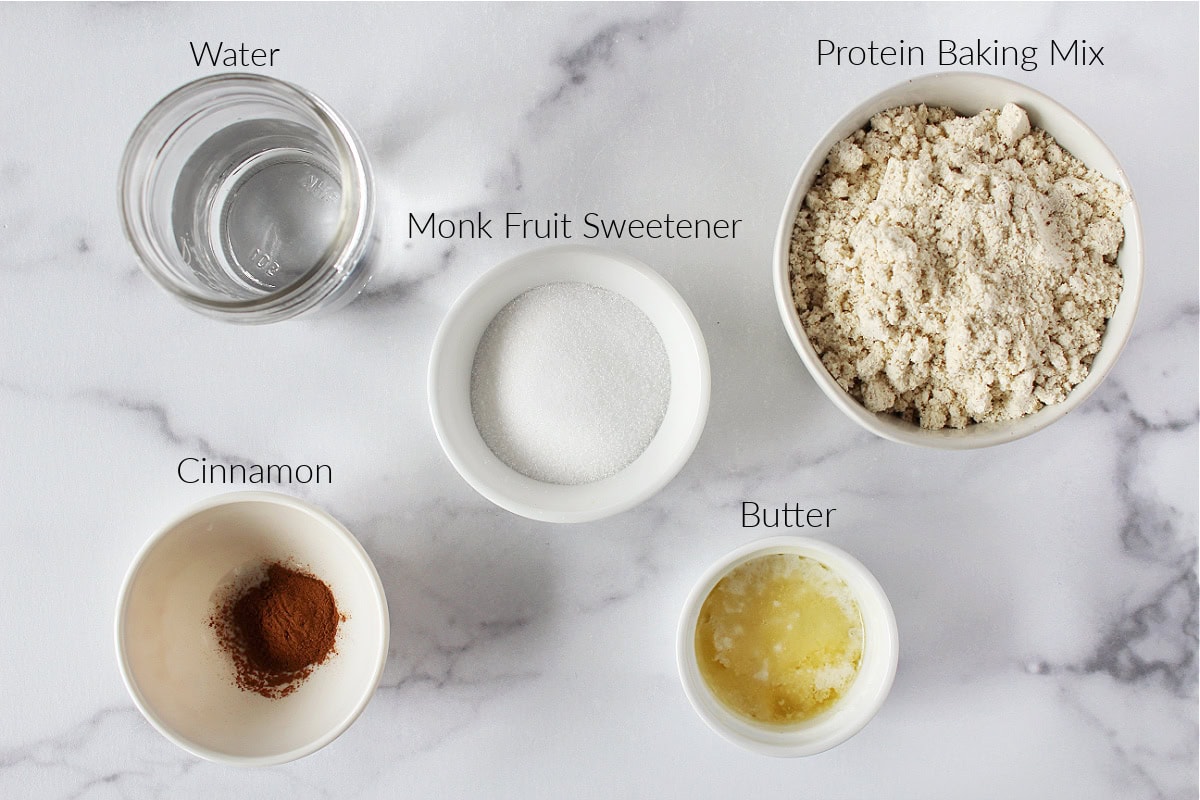 Labeled ingredients for cinnamon sugar protein donuts on a white marble countertop.