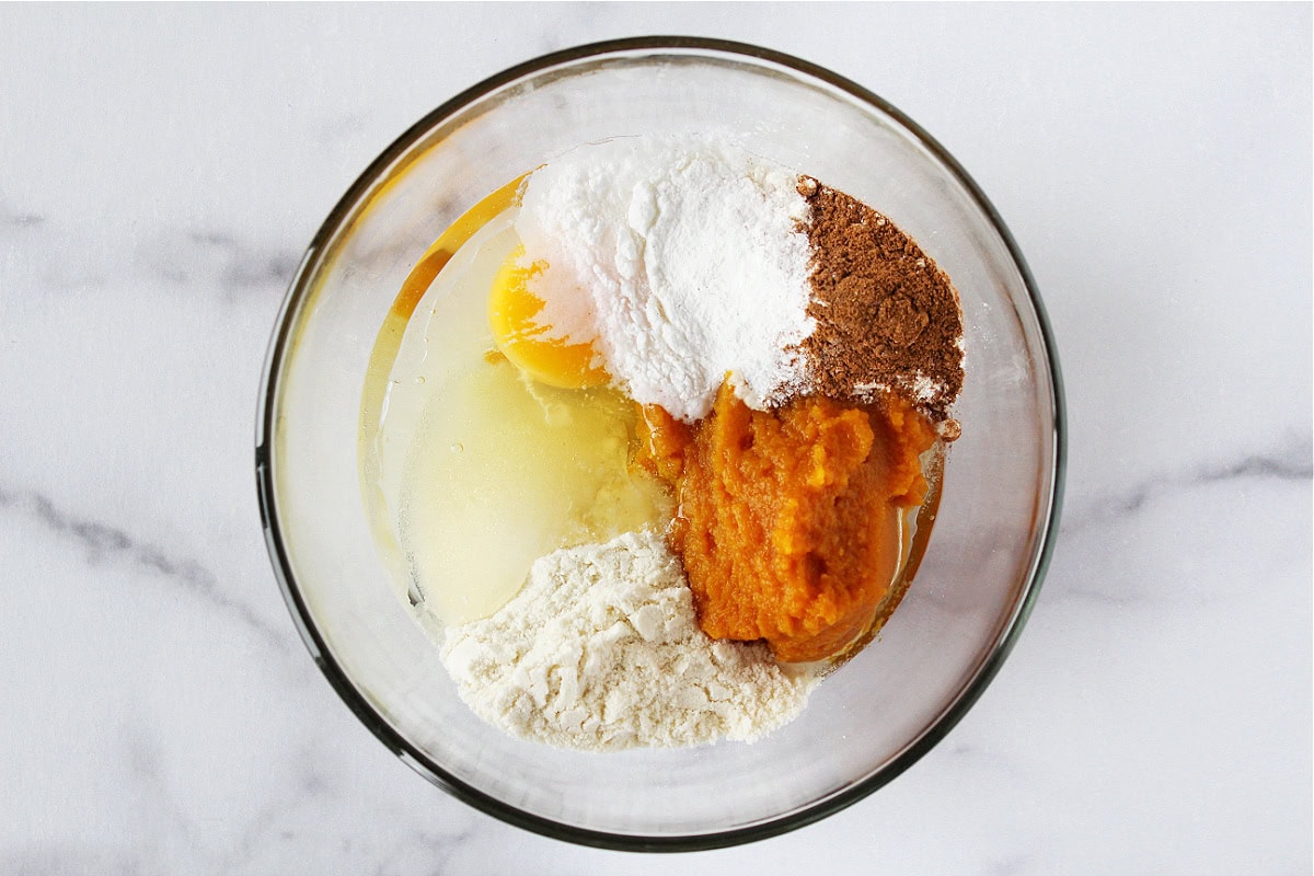 Pumpkin puree, egg, protein powder and coconut flour in glass bowl.