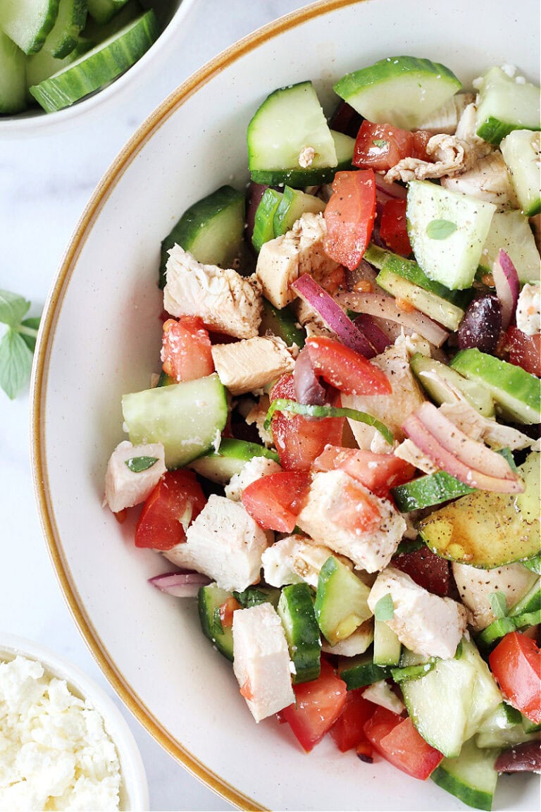 Grilled chicken breast, cucumbers and tomato in a bowl seasoned with salt and pepper.