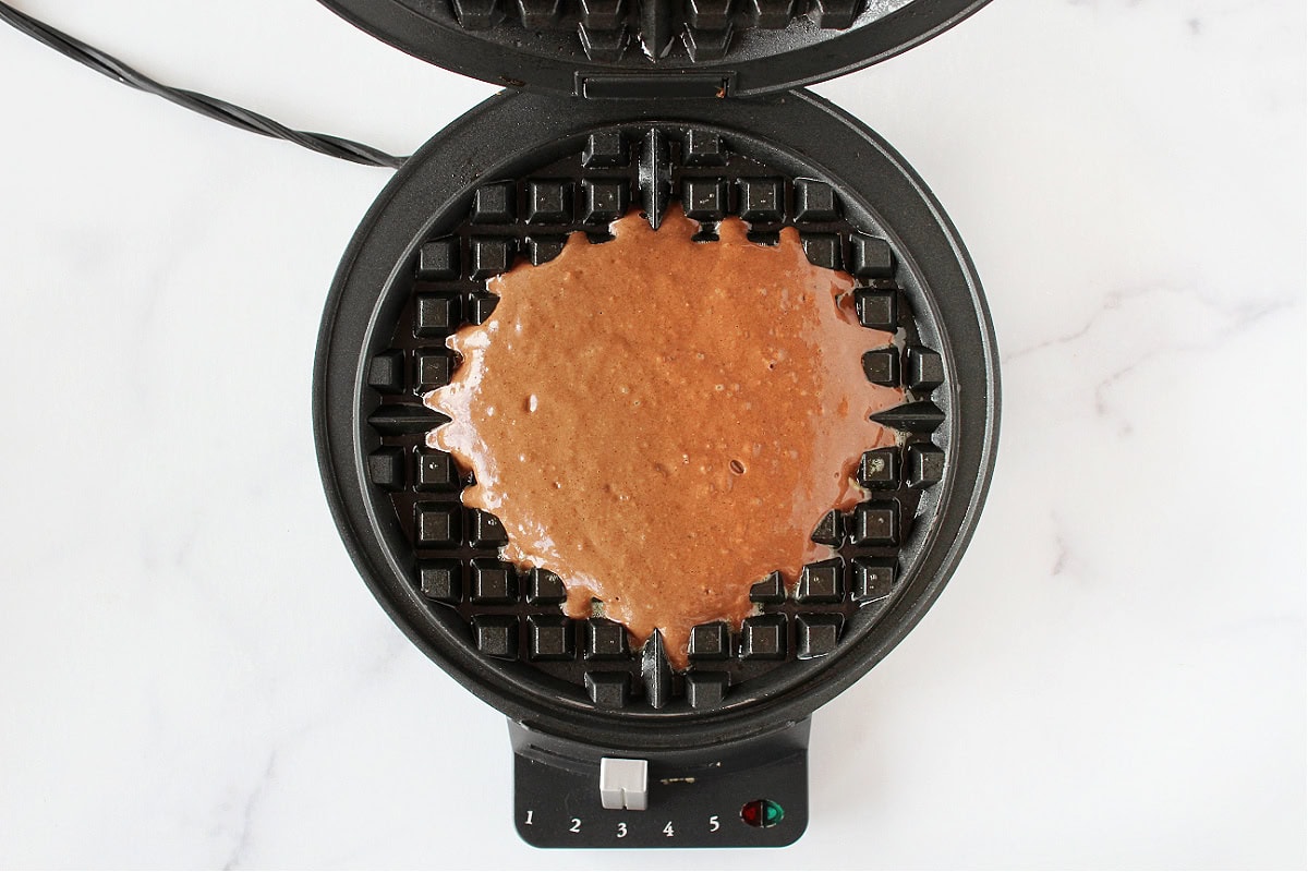Chocolate batter in a black waffle maker.