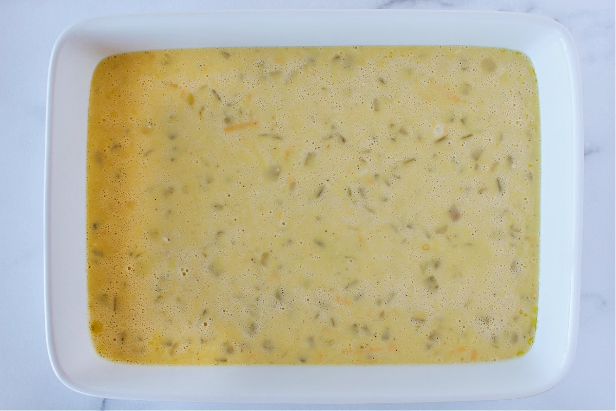 Egg bake batter with green chiles in a 9x13 white ceramic baking dish.