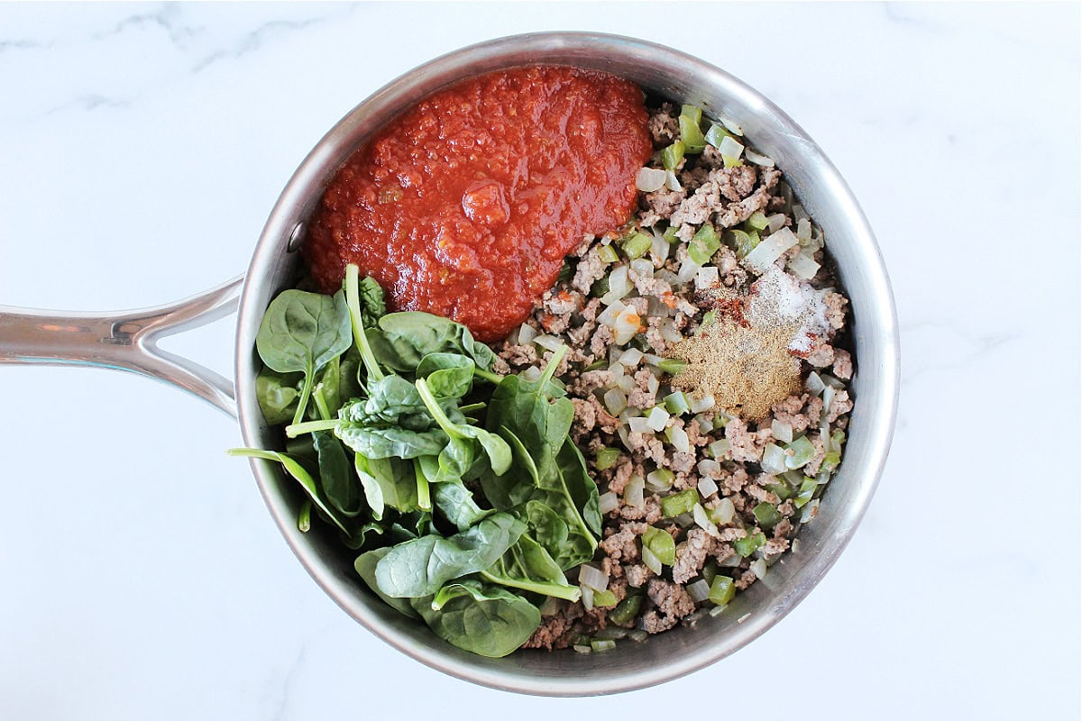 Salsa, spinach, browned ground beef, and spices in a saucepan.