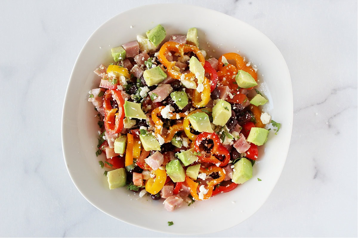 Diced avocado and crumbled feta on top of ham and black bean salad.