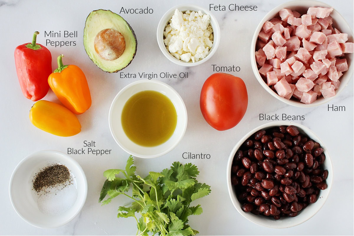 Labeled ingredients for ham and black bean salad on a white marble countertop.