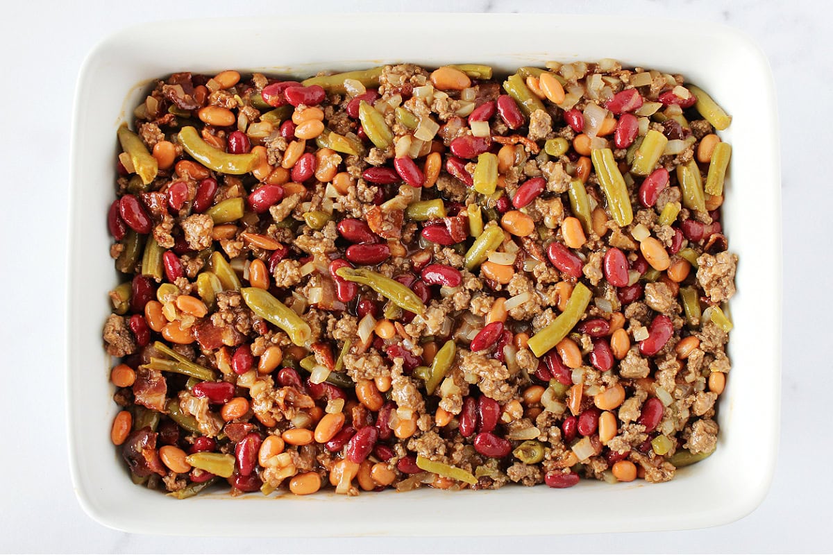 Unbaked calico beans in a white 9x13 baking dish.