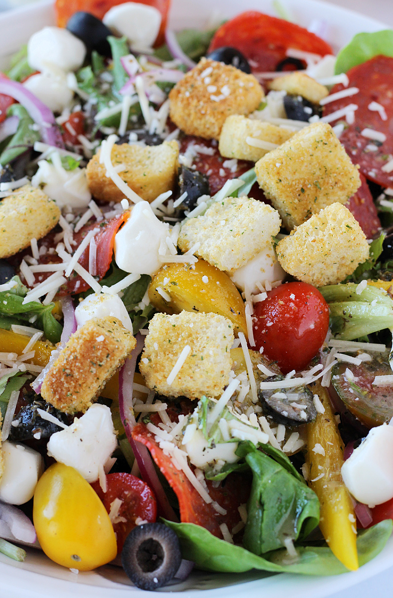 Croutons and Parmesan cheese topping a pizza salad in a bowl.