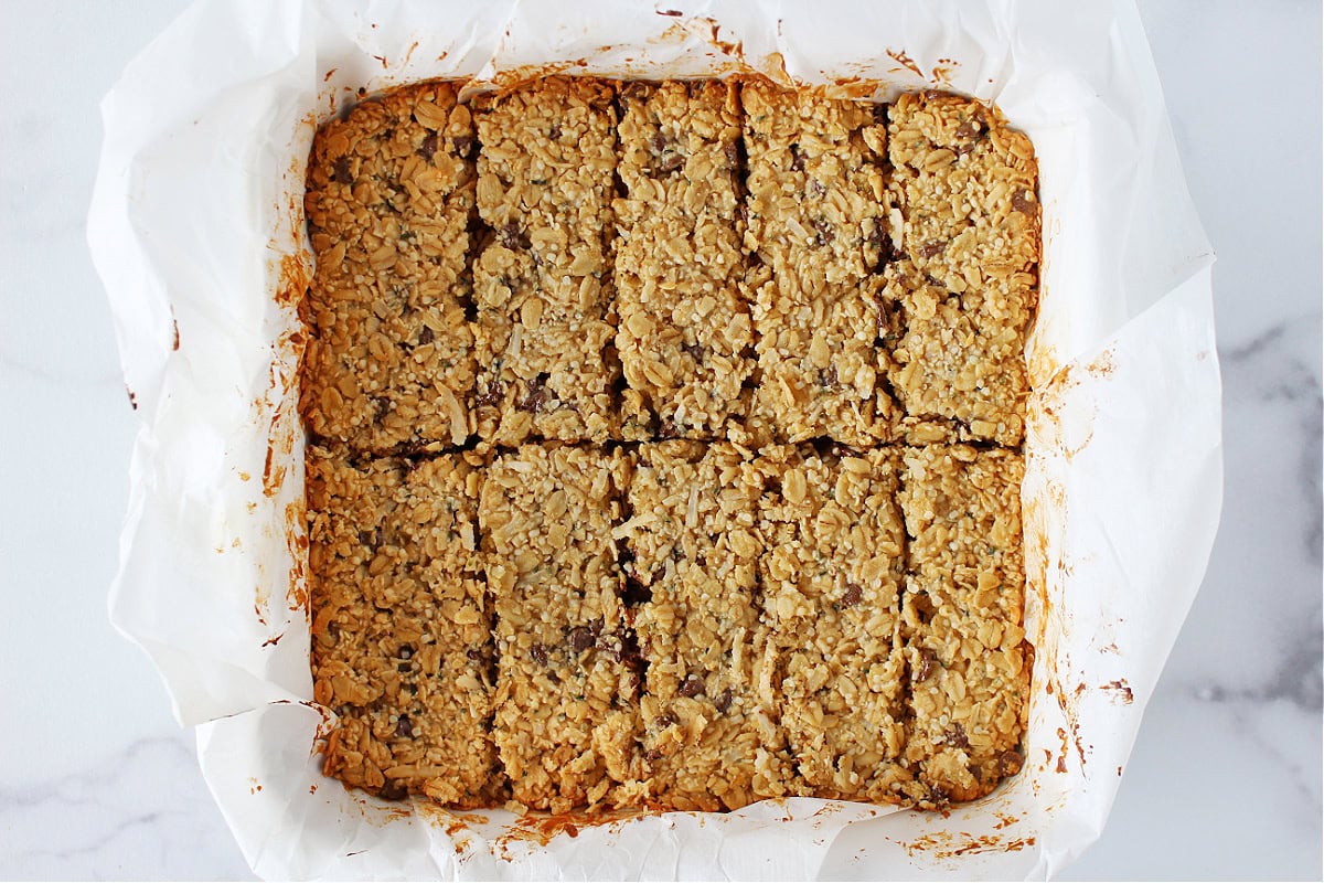 Baked granola bars fresh from the oven cut into slices in the pan.