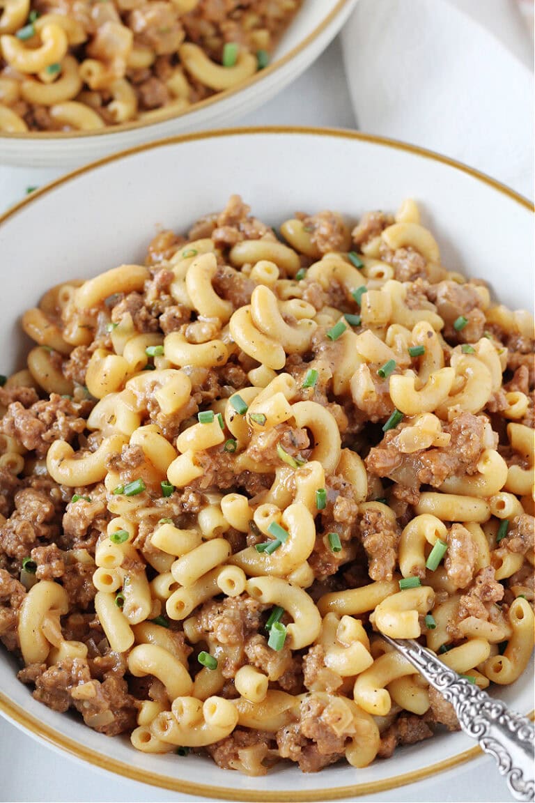 Hamburger helper topped with chives in bowls with a spoon.