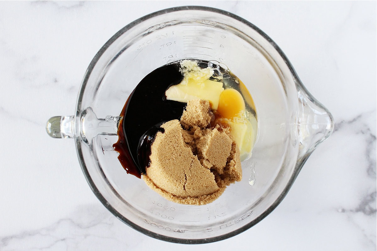 Butter, brown sugar, molasses, and an egg in a mixing bowl.