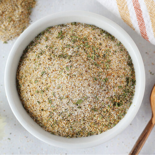 Burgers seasoning recipe in a white bowl with a copper spoon next to it.