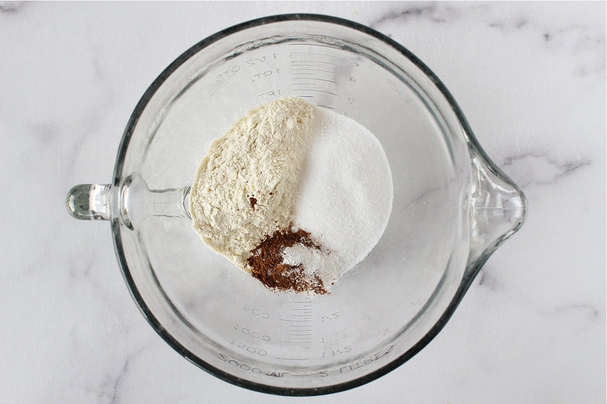 Flour, monk fruit sweetener, and pumpkin pie spice in a glass mixing bowl.