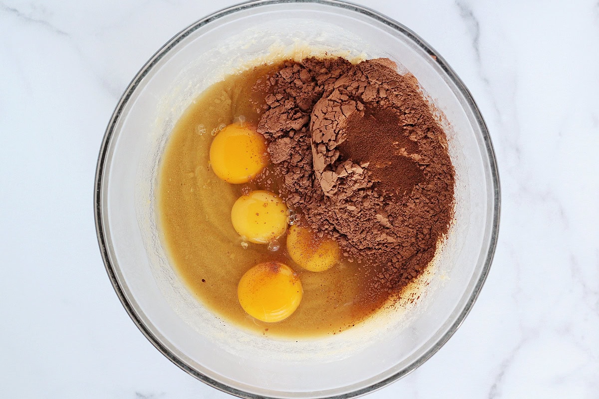 Eggs, cocoa powder and espresso powder on top of a sugar butter mixture.