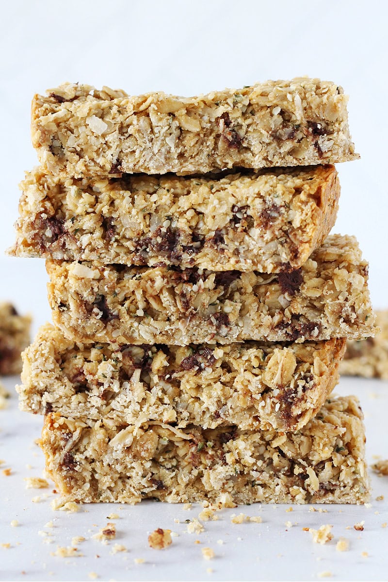 Five homemade granola bars stacked high on a white countertop.