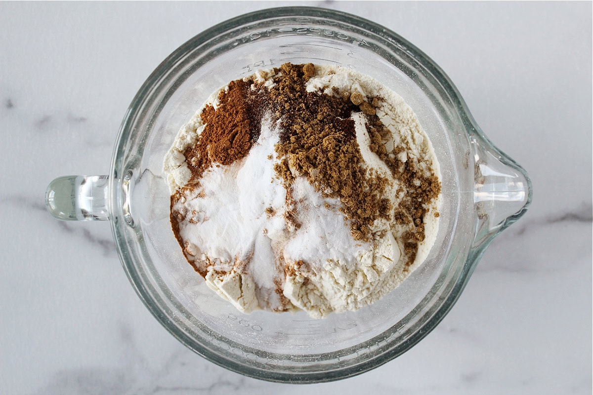 Flour, baking soda, and holiday spices in a glass bowl.