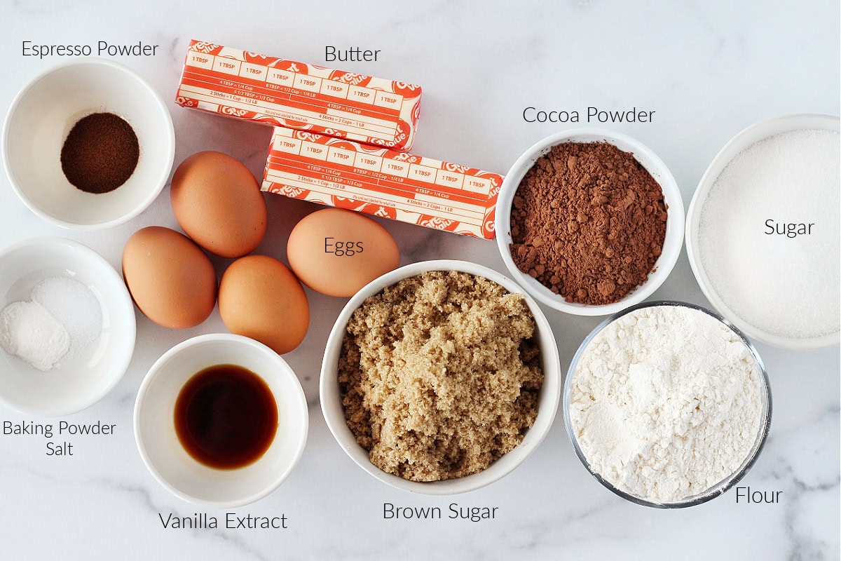 Labeled ingredients for chocolate brownies on a white marble countertop.