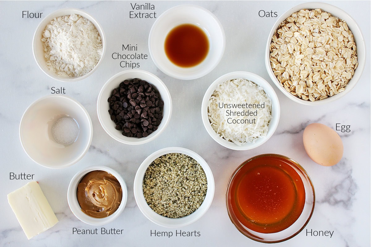 Labeled ingredients for healthy homemade granola bars on a white marble countertop.