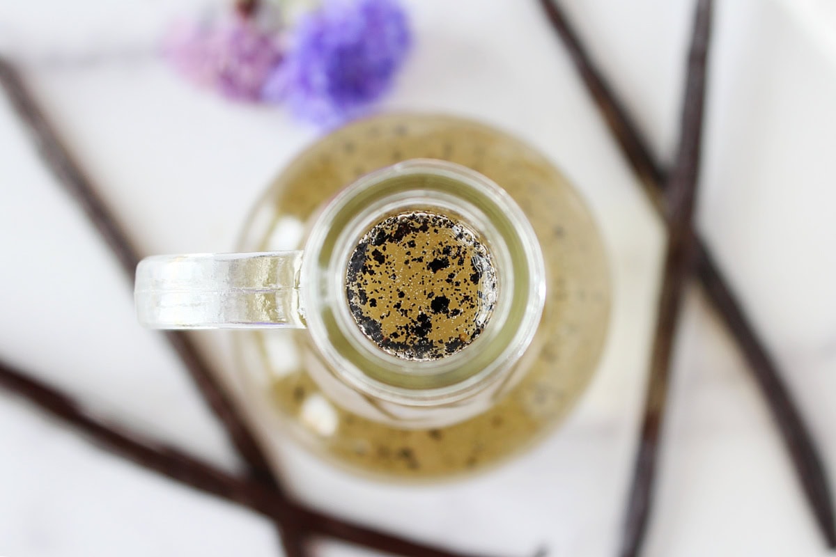 Looking down into a glass bottle of homemade vanilla bean syrup.