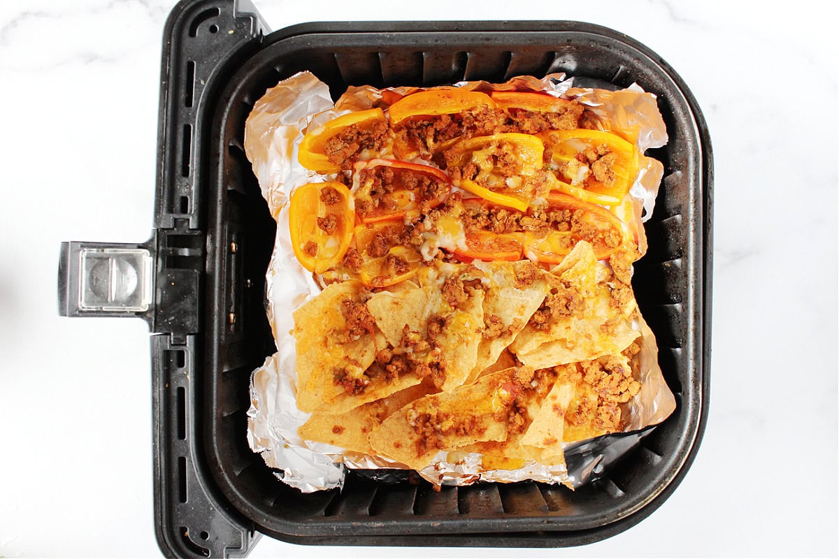 Taco meat and melted cheese on tortilla chips and mini bell pepper halves.