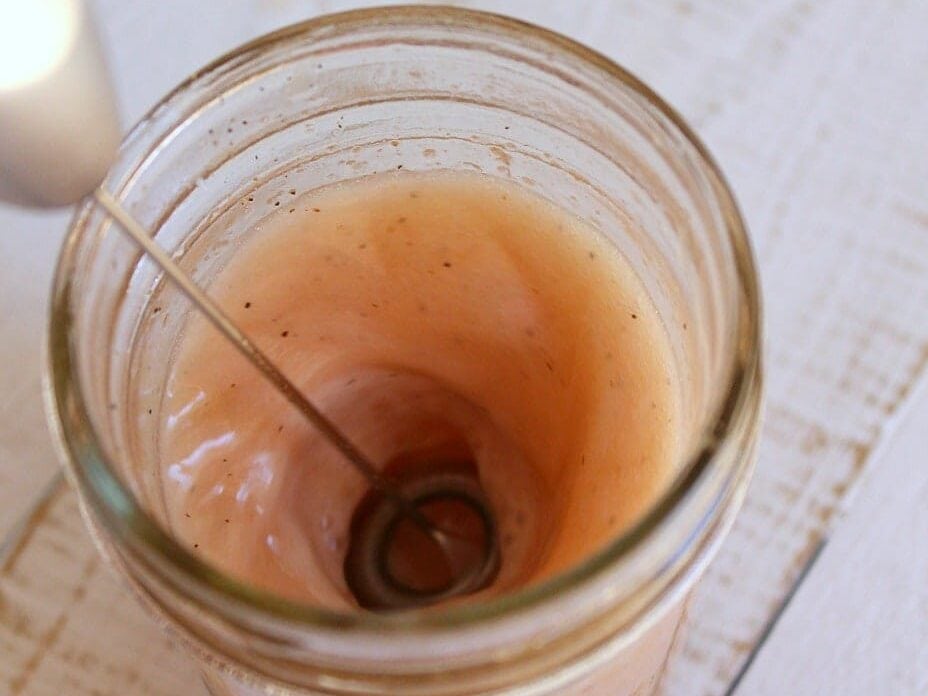Using a hand frother to mix a light salad dressing in a jar.