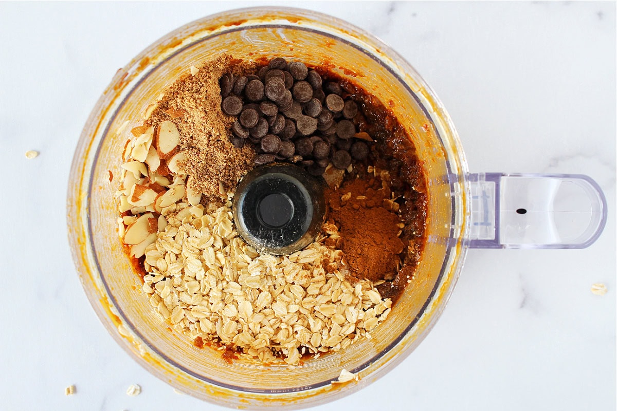 Oats, sliced almonds and chocolate chips over date batter in a food processor.