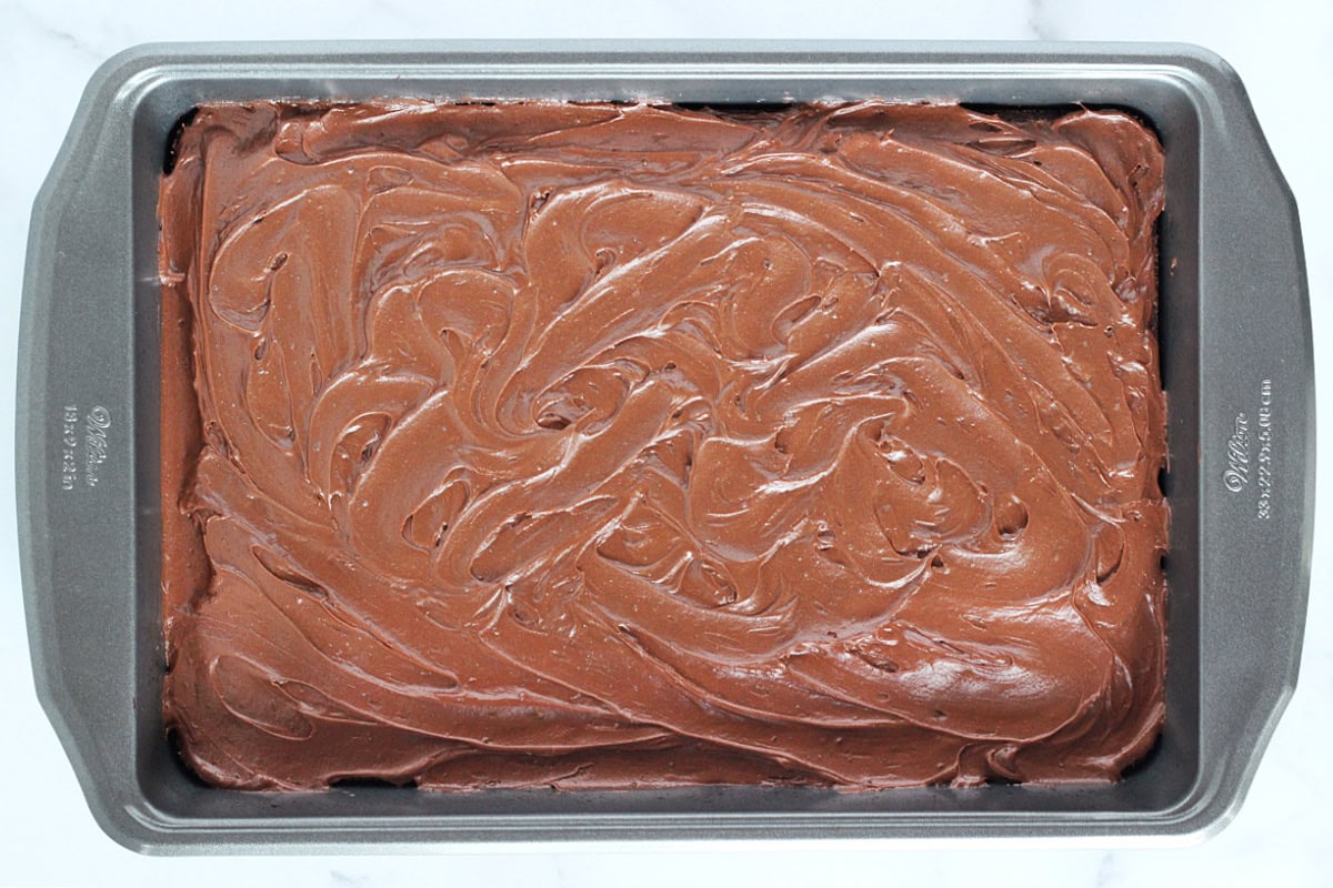 A 9x13 metal pan with swirly chocolate frosting on top of brownies.
