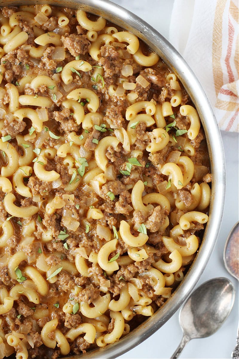 Homemade hamburger helper in a stainless steel pan topped with parsley.