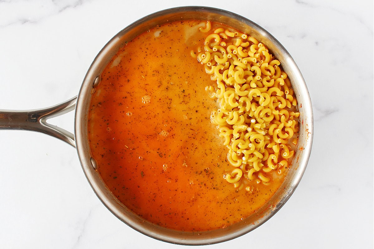 Uncooked elbow noodles in beef broth and milk.