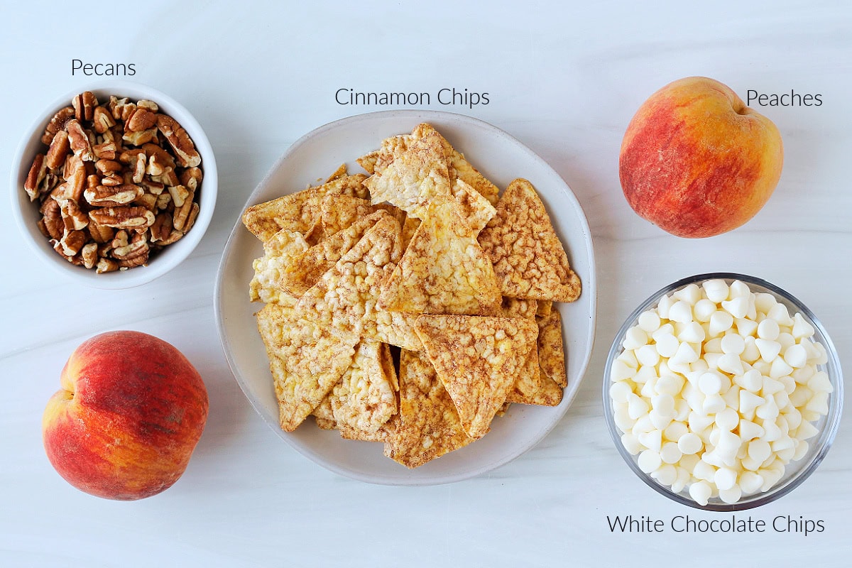 Labeled ingredients for dessert peach nachos with white chocolate on a countertop.