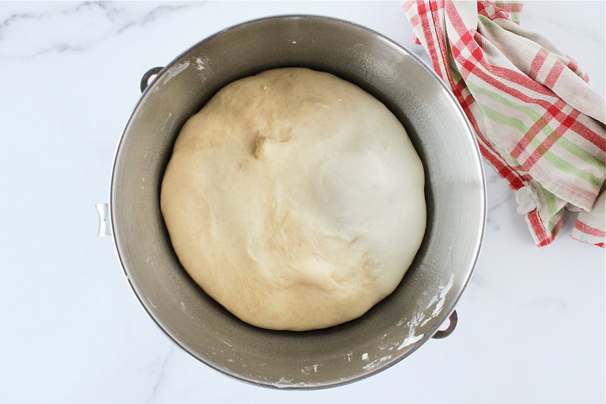 Proofed sourdough bread dough in a stand mixer bowl.