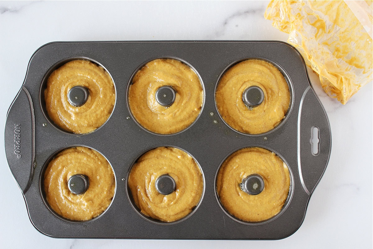 Pumpkin batter in a 6-hole donut pan.