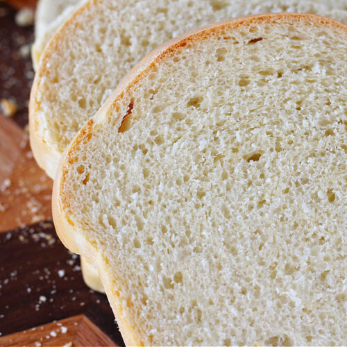 Sourdough sandwich bread slices on a wooden cutting board.