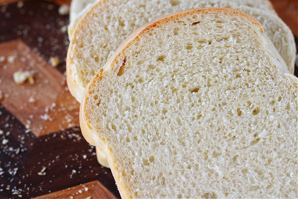 Sourdough sandwich bread slices on a wooden cutting board.
