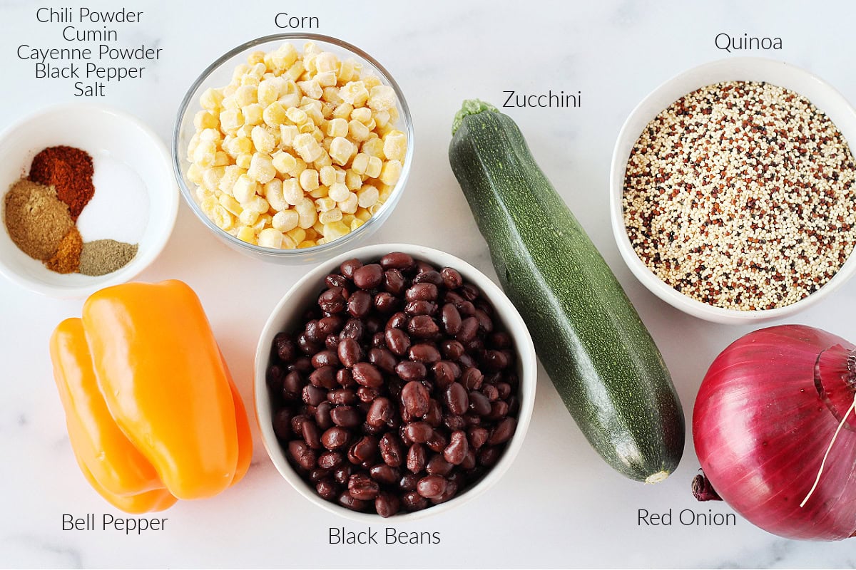 Labeled ingredients for southwest quinoa salad on a white marble countertop.