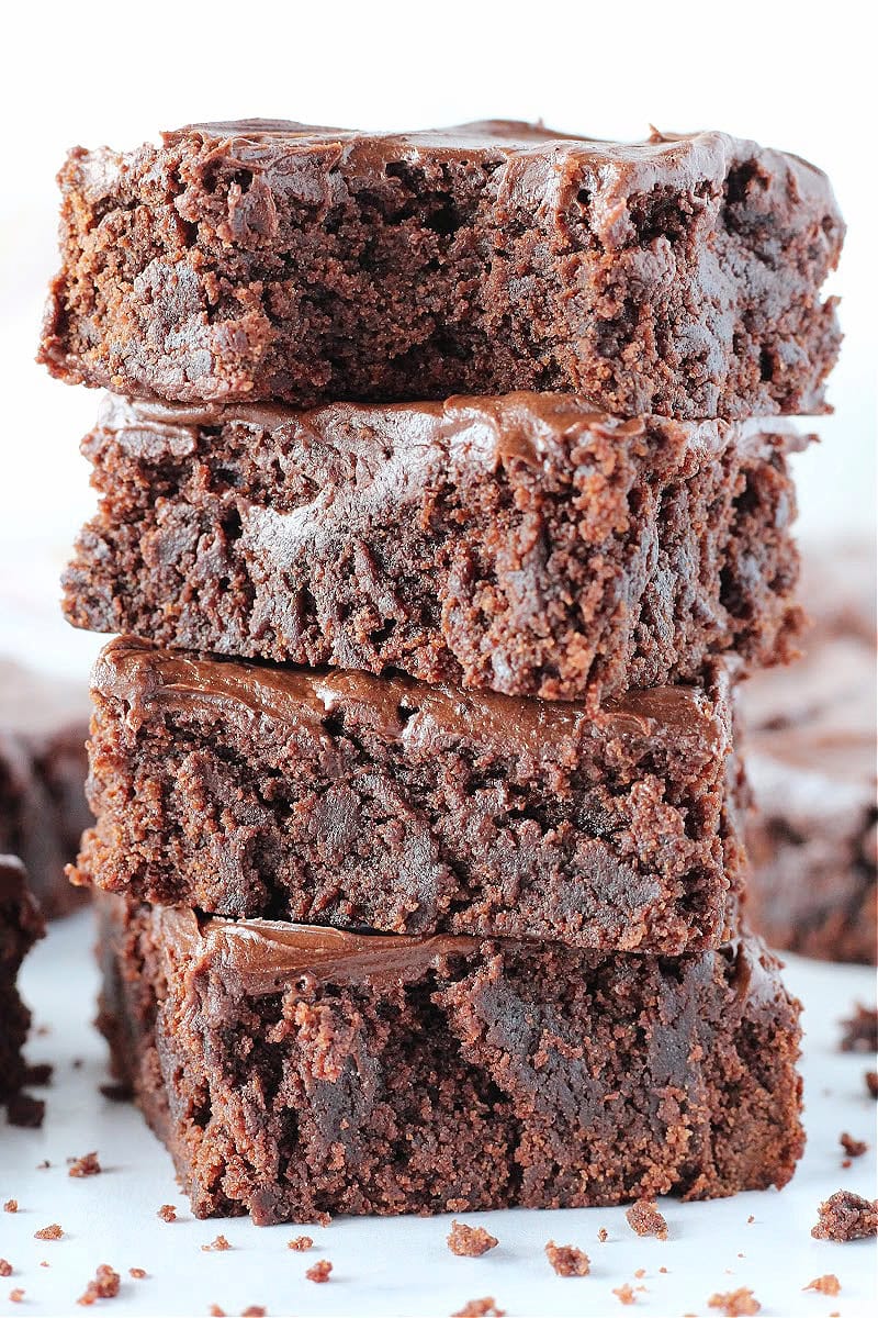 A stack of four chocolate frosted brownies.