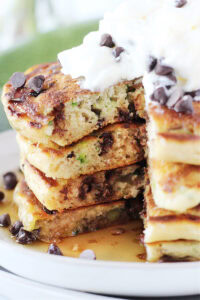 Four zucchini pancakes stacked with a slice taken out.