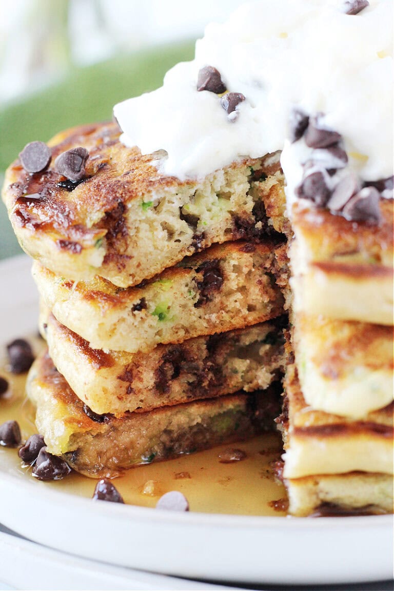 Four zucchini pancakes stacked with a slice taken out.