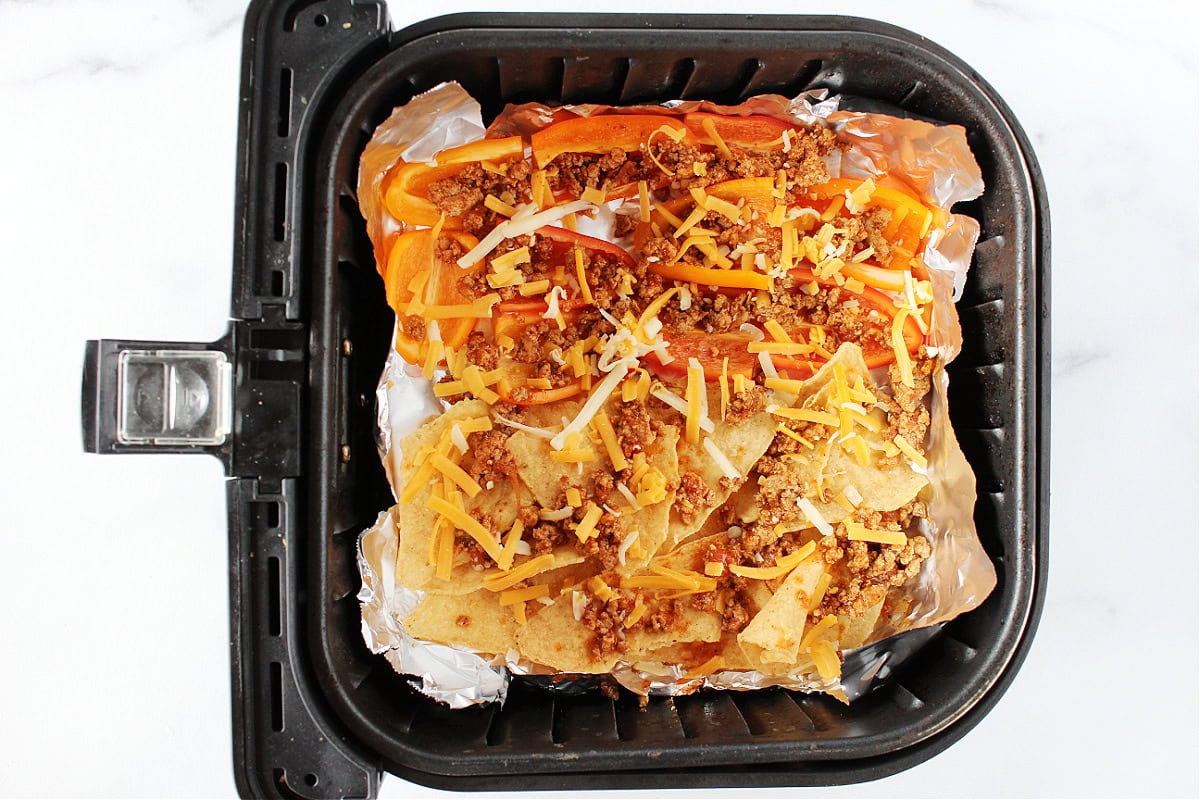 Taco meat and shredded cheese on tortilla chips and bell pepper slices.