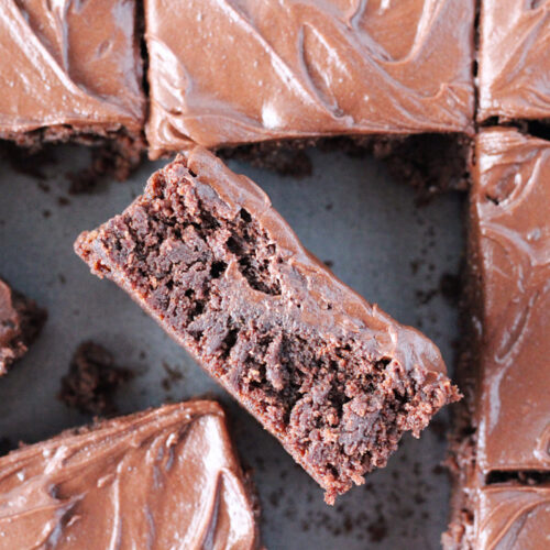 A chocolate frosted brownie on it's side in the brownie pan.