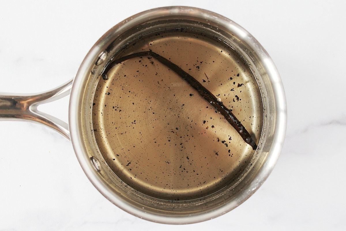 Clear vanilla bean coffee syrup in a small soup pot with a vanilla bean pod.
