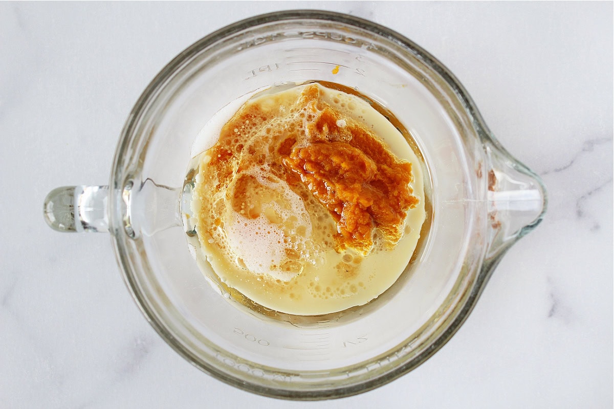 Pumpkin puree, milk and oil in a glass mixing bowl.