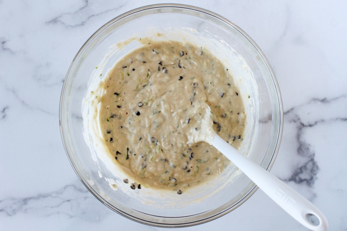 Chocolate chip zucchini pancake batter in a bowl with a white silicone spatula.