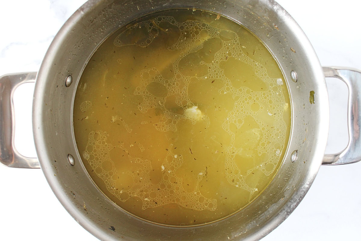 Chicken broth in a metal soup pot.