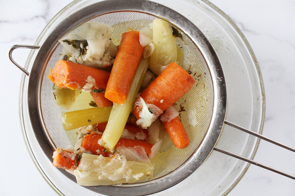 Cooked veggies in a metal strainer over a bowl.